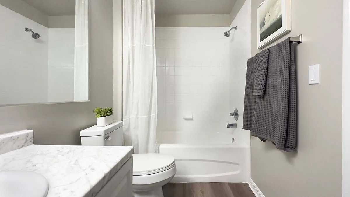 Guest bathrooms offer luxurious space with large mirrors, wood-style flooring, and a cozy shower/tub combo. 