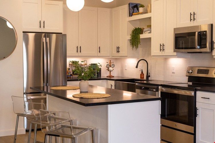 a kitchen with white cabinets and a large island with a black countertop