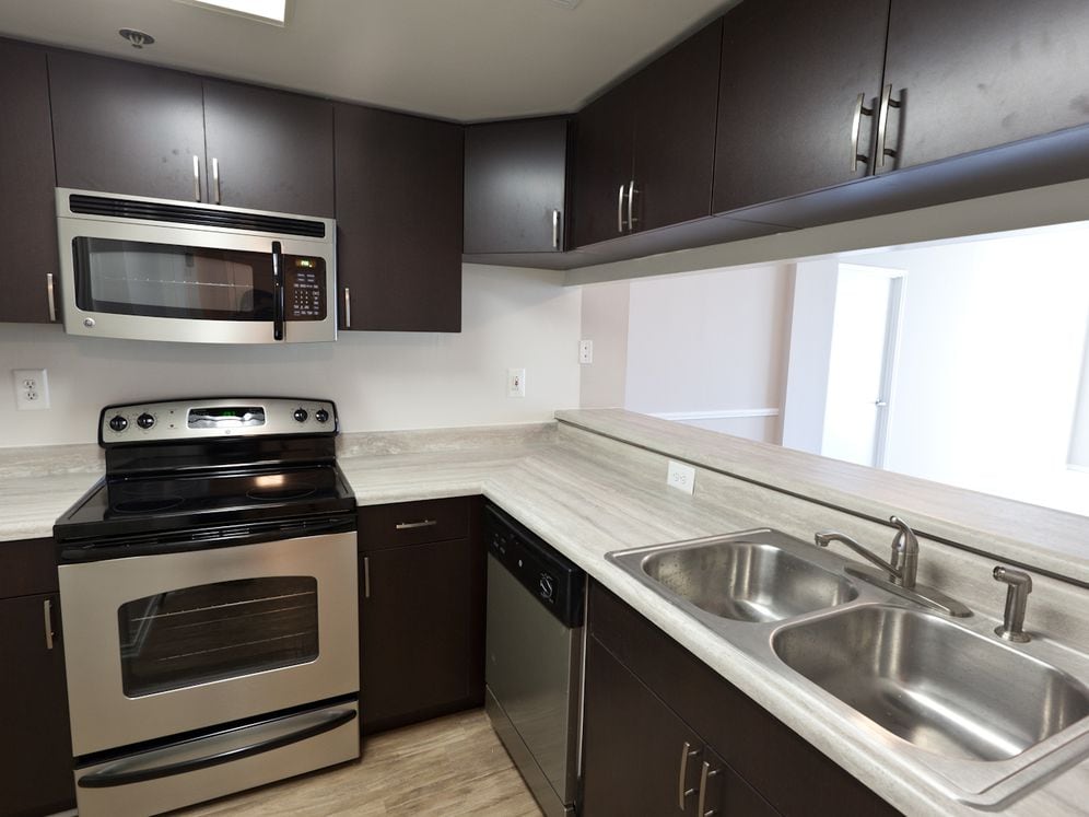 Classic Package II kitchen with grey countertops, espresso cabinetry, stainless-steel appliances, and hard surface flooring (select homes)