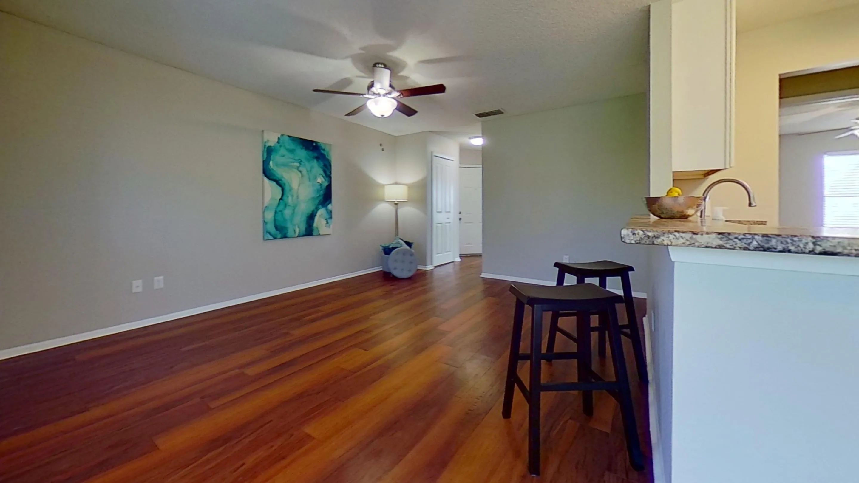 Enjoy the open and airy living space in the Martinique Autograph floor plan. With beautiful wood-style flooring, a ceiling fan, and contemporary decor, this living room is perfect for relaxation and entertainment.