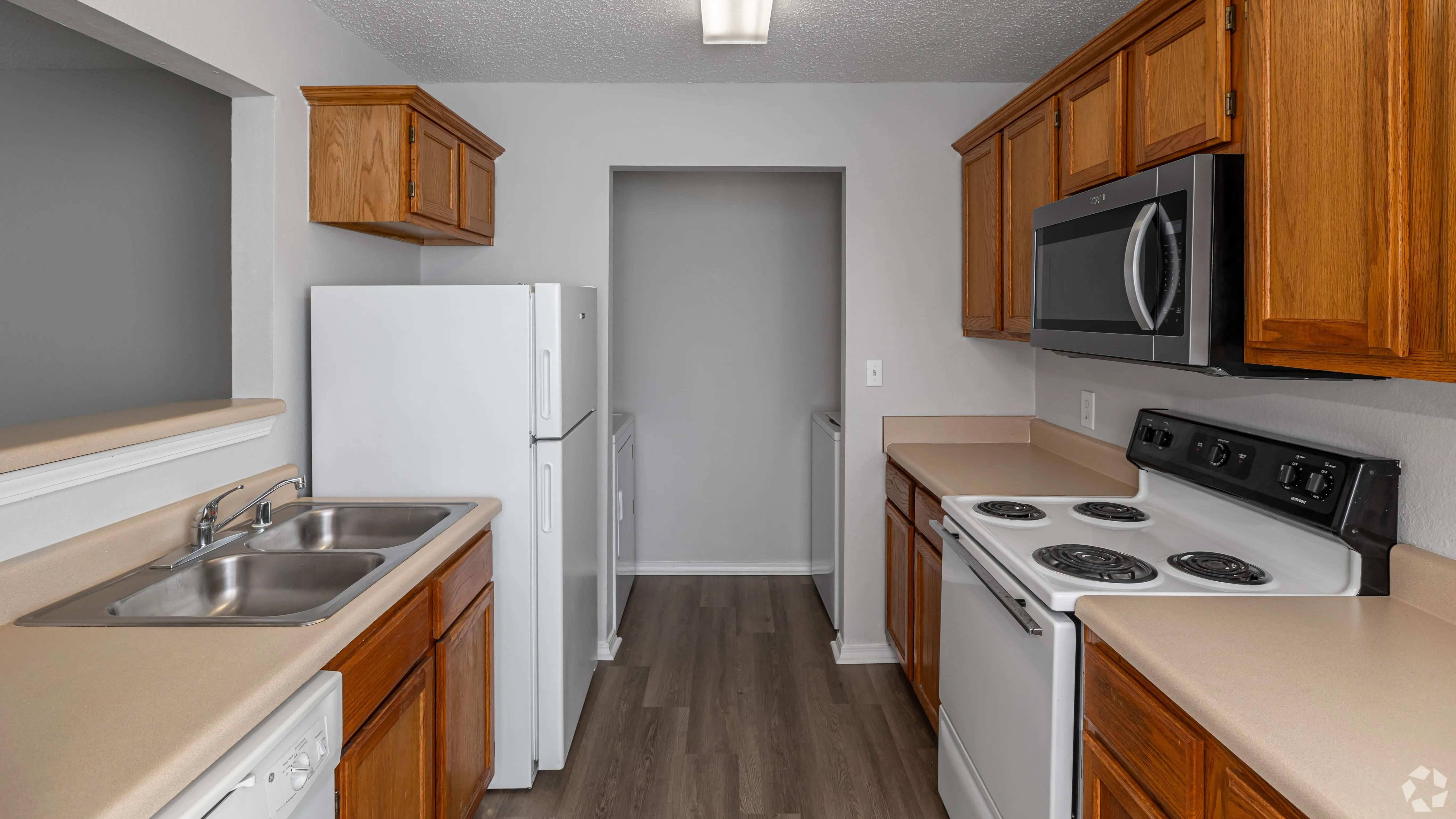 Cook in comfort with this galley-style kitchen featuring classic wood cabinetry, full-size appliances, and plenty of counter space.