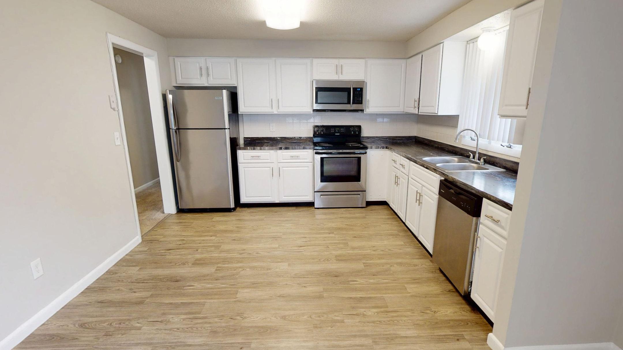 Cook and entertain with ease in The Pioneer’s full-size kitchen featuring stainless steel appliances, white cabinetry, and wood-style flooring.