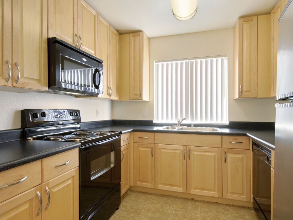 Kitchens with black appliances, black laminate countertops, and maple cabinetry