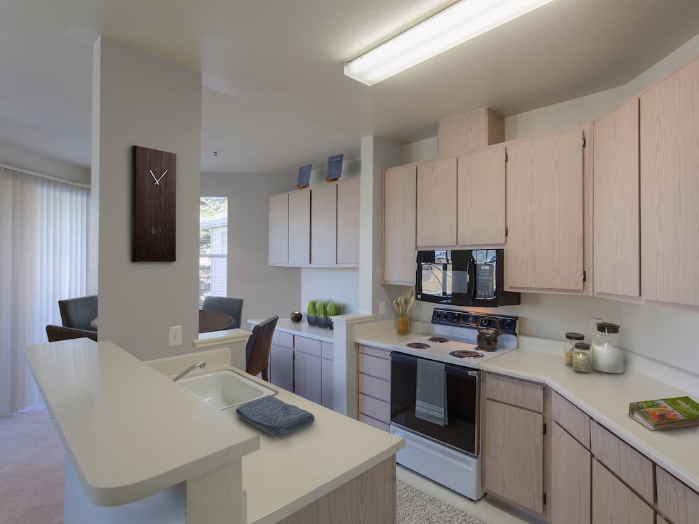 Classic Package I kitchen with light oak cabinetry, white laminate countertops, black appliances, and hard surface flooring