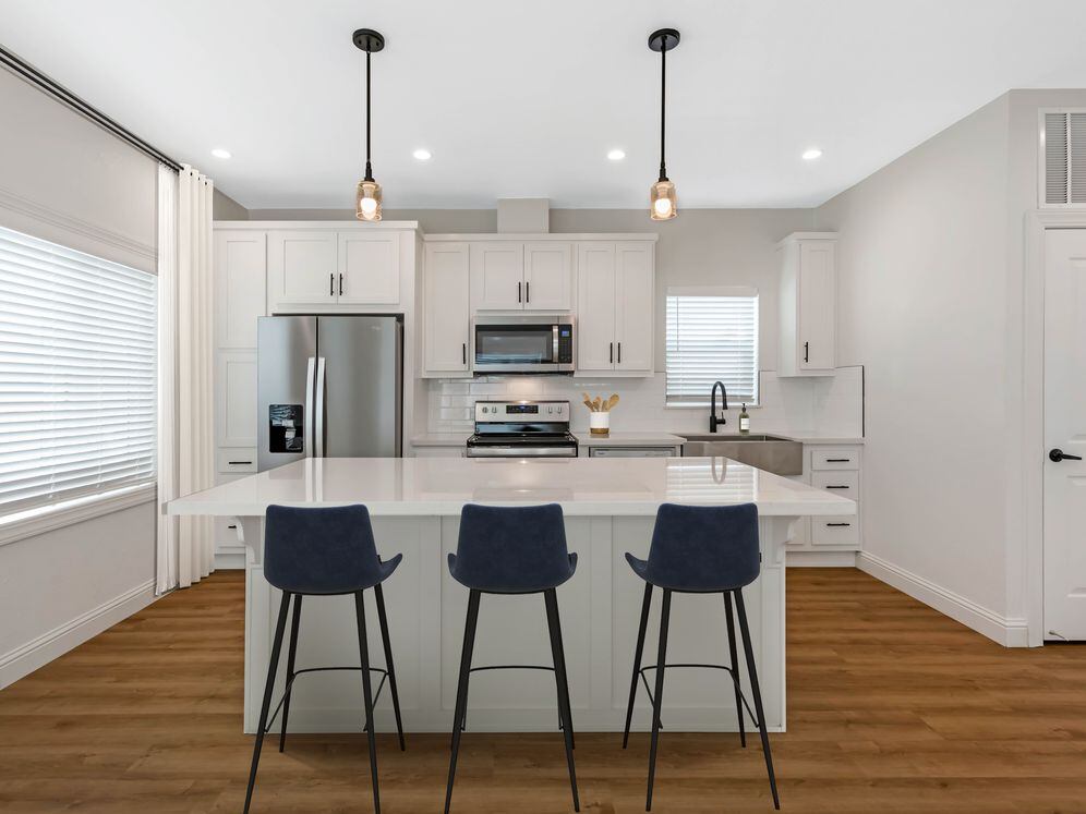Freestanding Home kitchen with white cabinetry, white quartz countertops, white subway tile backsplash, stainless steel appliances, and hard surface flooring