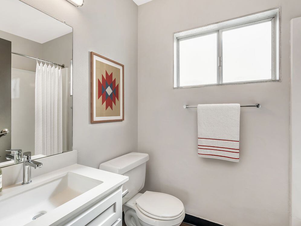 Renovated Package I bath with white quartz countertops, white cabinetry, and hard surface flooring (select homes)