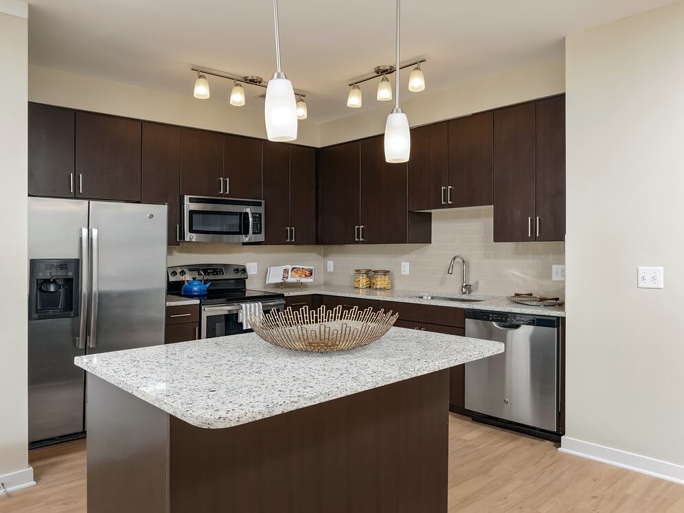 Classic Package II townhome kitchen with stainless steel appliances, espresso cabinetry, white speckled granite countertops, and hard surface flooring