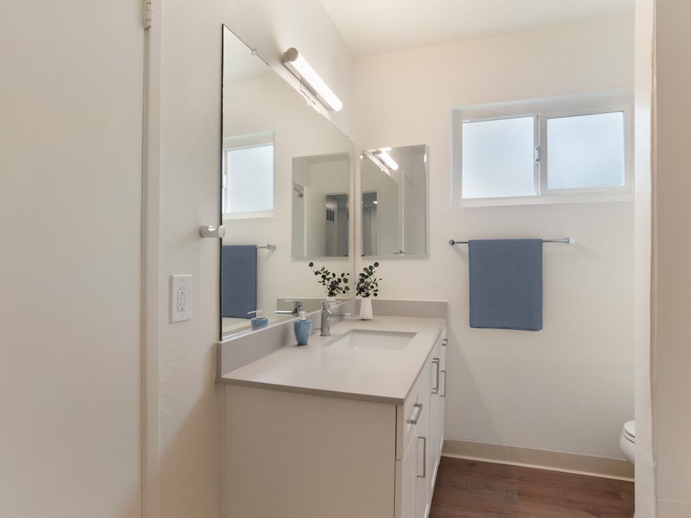 Renovated Package I bath with white cabinetry, beige granite countertops, and hard surface flooring
