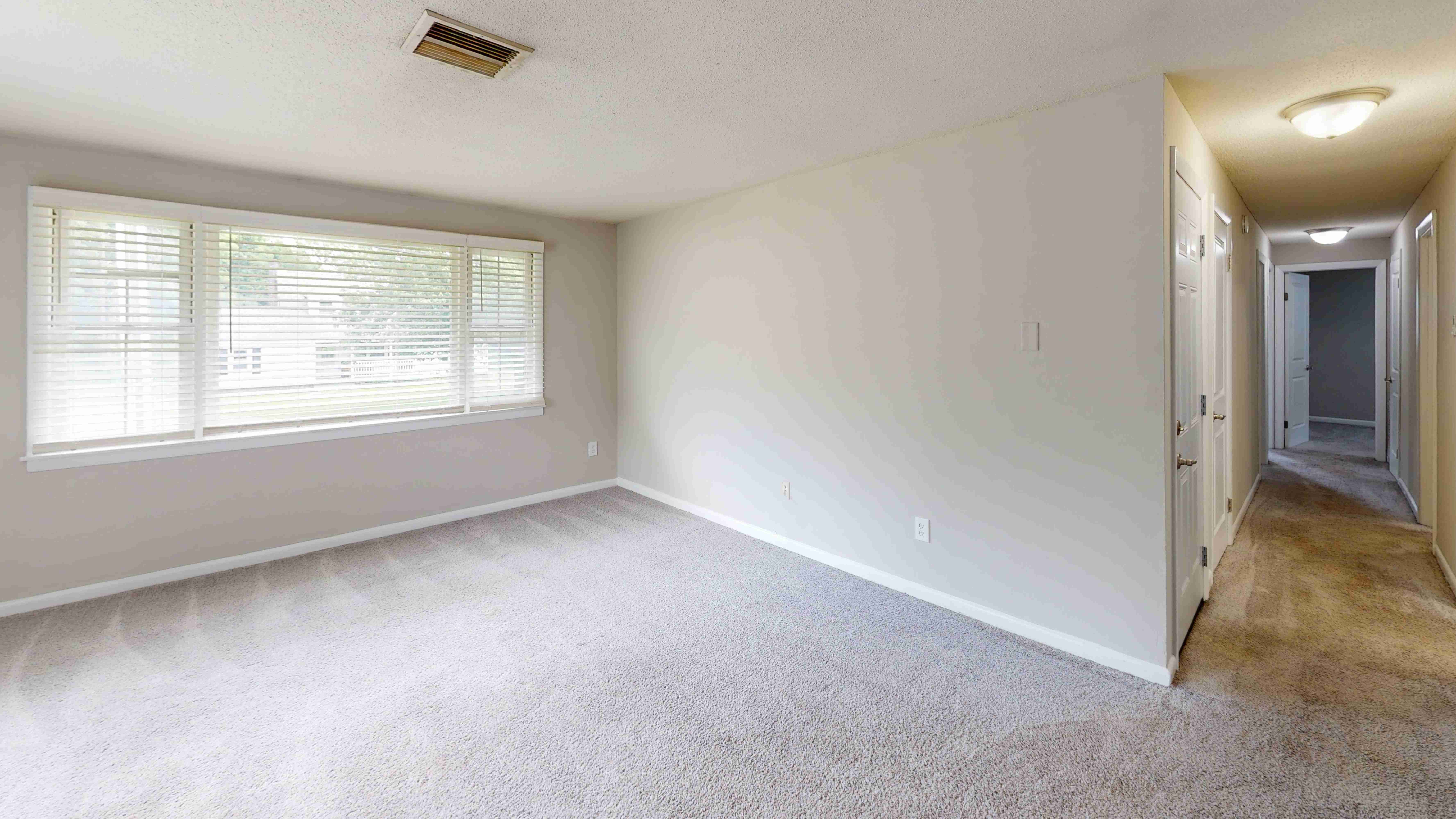 The Pioneer floor plan features a bright and open living room with plush carpeting and easy access to bedrooms and bathrooms down the hall.