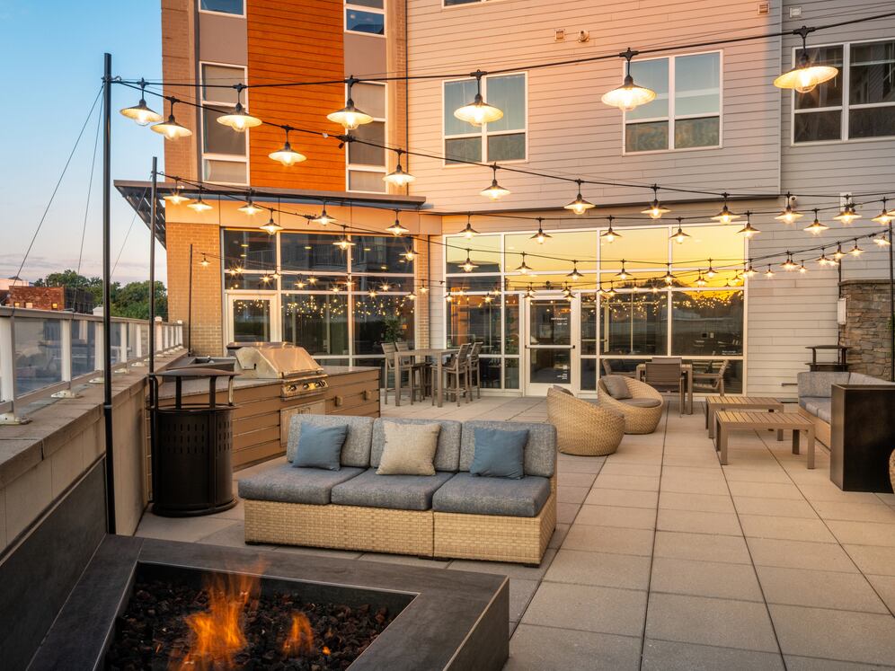Rooftop patio with BBQ grills, lounge seating, and firepit