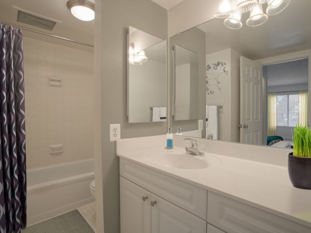 Bathroom with white countertops, white cabinetry and tiled bathtub