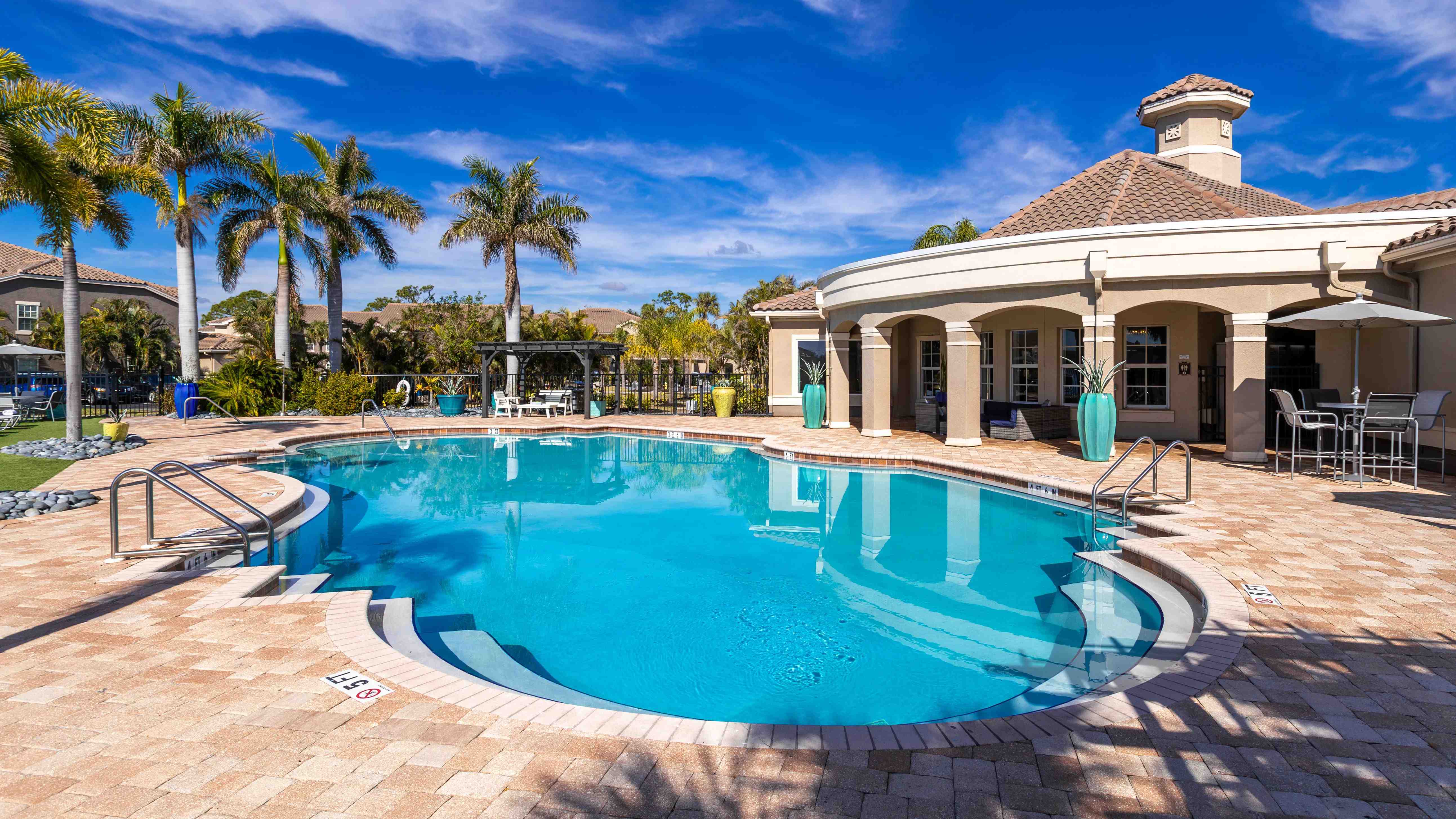 Enjoy the perfect poolside escape with an expansive sundeck, lounge seating, and lush greenery.
