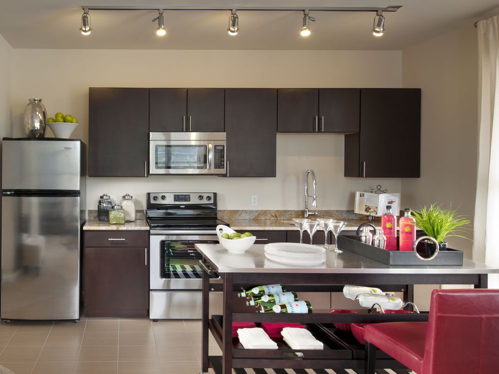 Open concept kitchen with espresso cabinetry, granite countertops, stainless-steel appliances, movable island and hard surface flooring