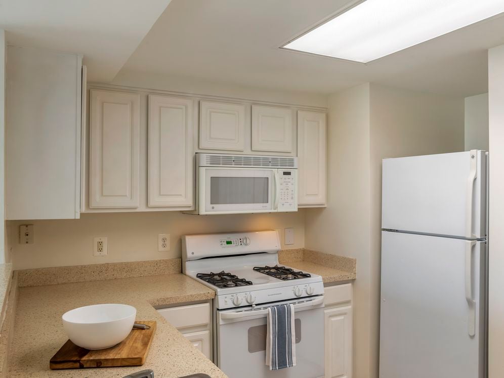 Classic Package I kitchen and living areas with white cabinetry, beige laminate countertops, white appliances, and tile flooring