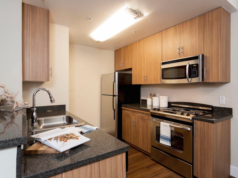 Classic Package III kitchen with stainless steel appliances, black speckled granite countertops, oak cabinetry, and hard surface flooring