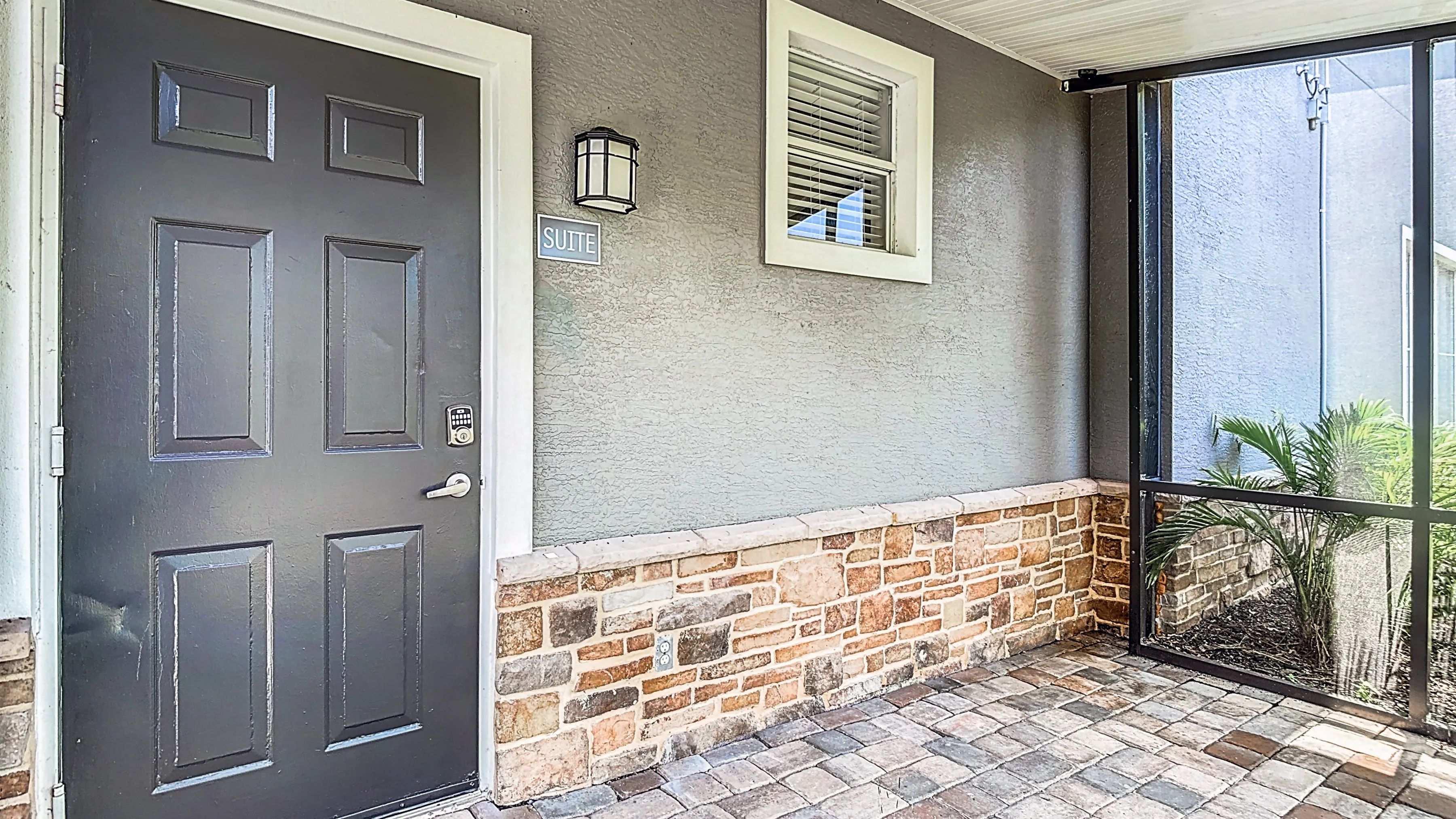The Suite entrance offers a charming and secure entry to your home with stone accents and a cozy screened in patio