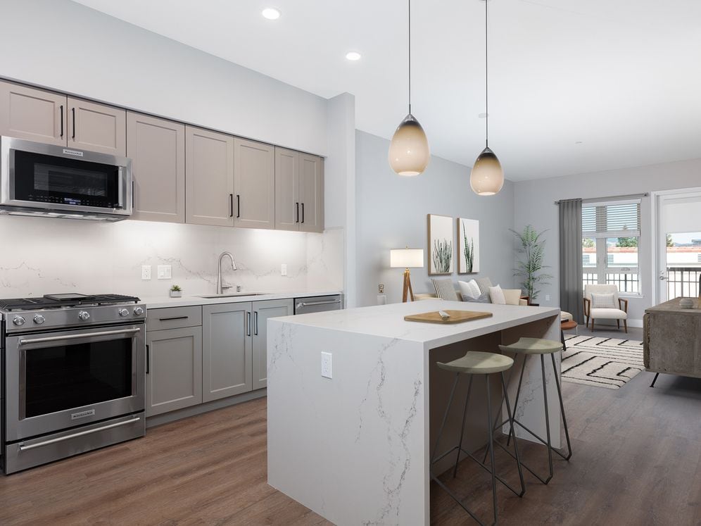 Signature Collection kitchen with upgraded stainless steel appliances, grey cabinetry, white marble countertops and backsplash, and hard surface flooring 