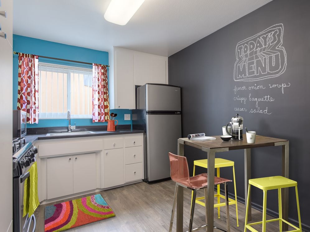 Classic Package III kitchen with stainless steel appliances, black quartz countertops, white cabinetry, and hard surface flooring (select homes)