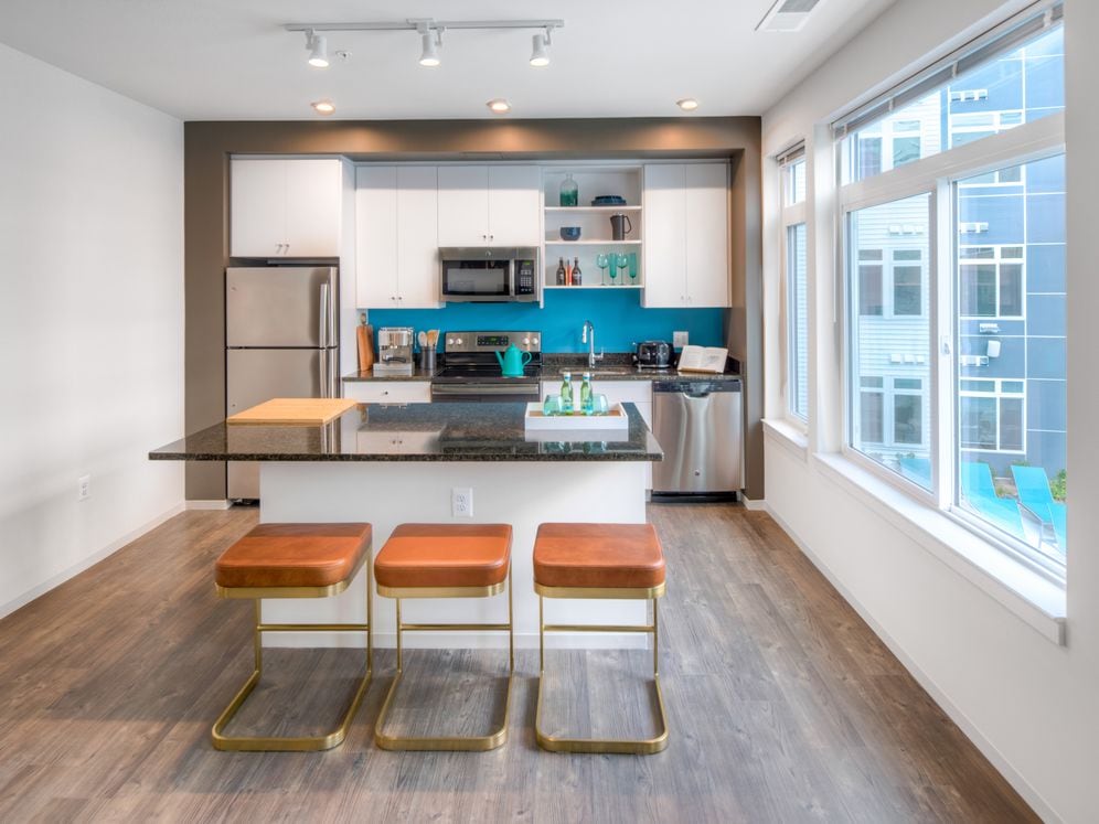 Kitchen with white cabinetry, granite countertops, island, stainless steel appliances and hard surface flooring