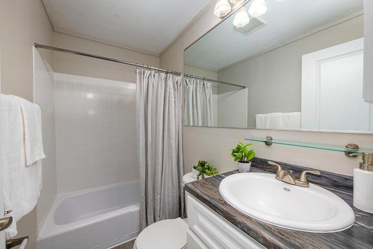 Our newly remodeled bathrooms feature black fusion countertops, wood-style flooring, and a large mirror.