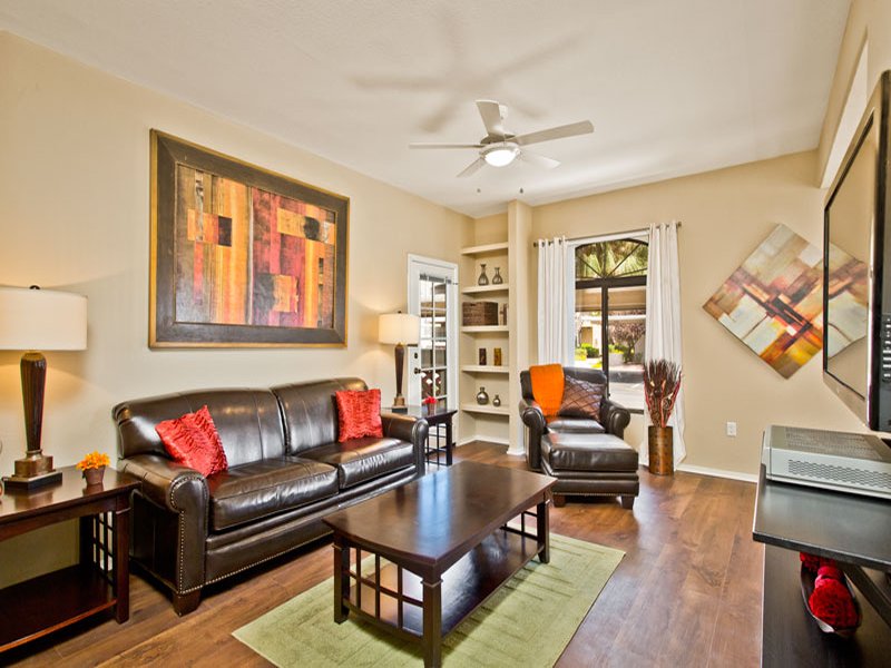 Spacious living room featuring ceiling fan and wood flooring available in select apartments
