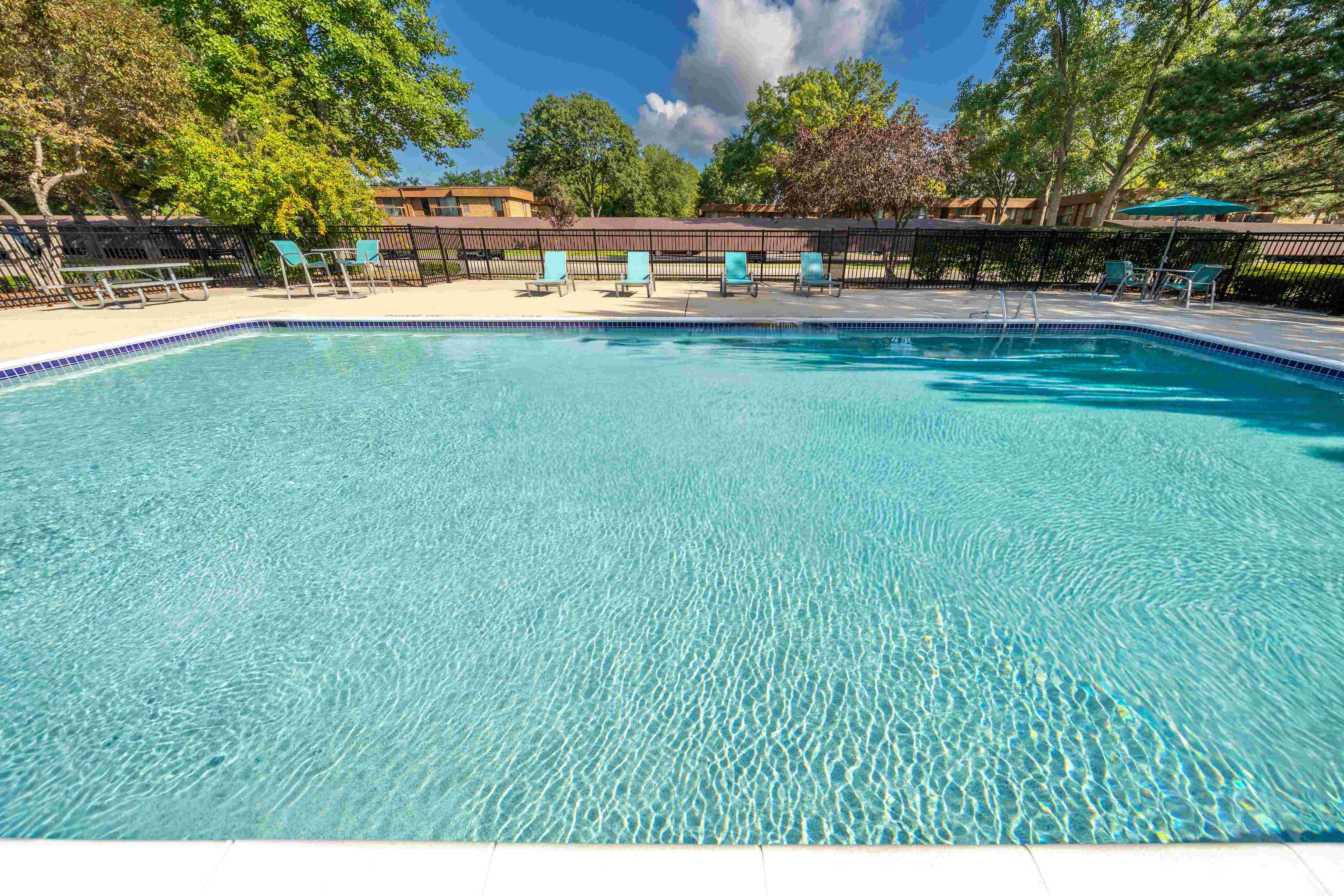 Heated pool equipped with comfy lounge chairs at Westwood Village Apartments in Westland, MI