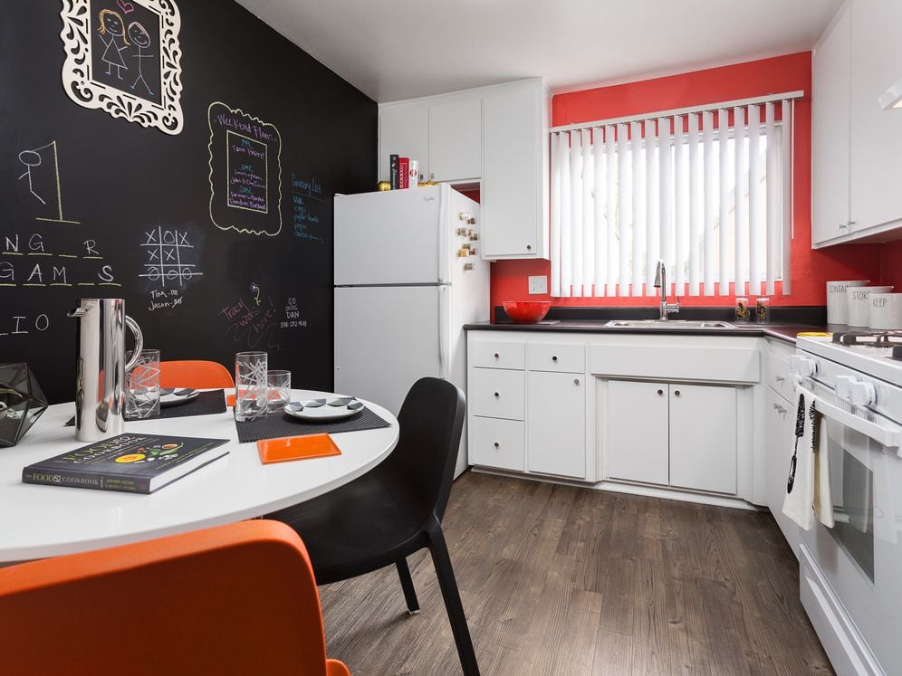 Classic Package II kitchen with white or black appliances, black laminate countertops, white cabinetry, and hard surface flooring (select homes)