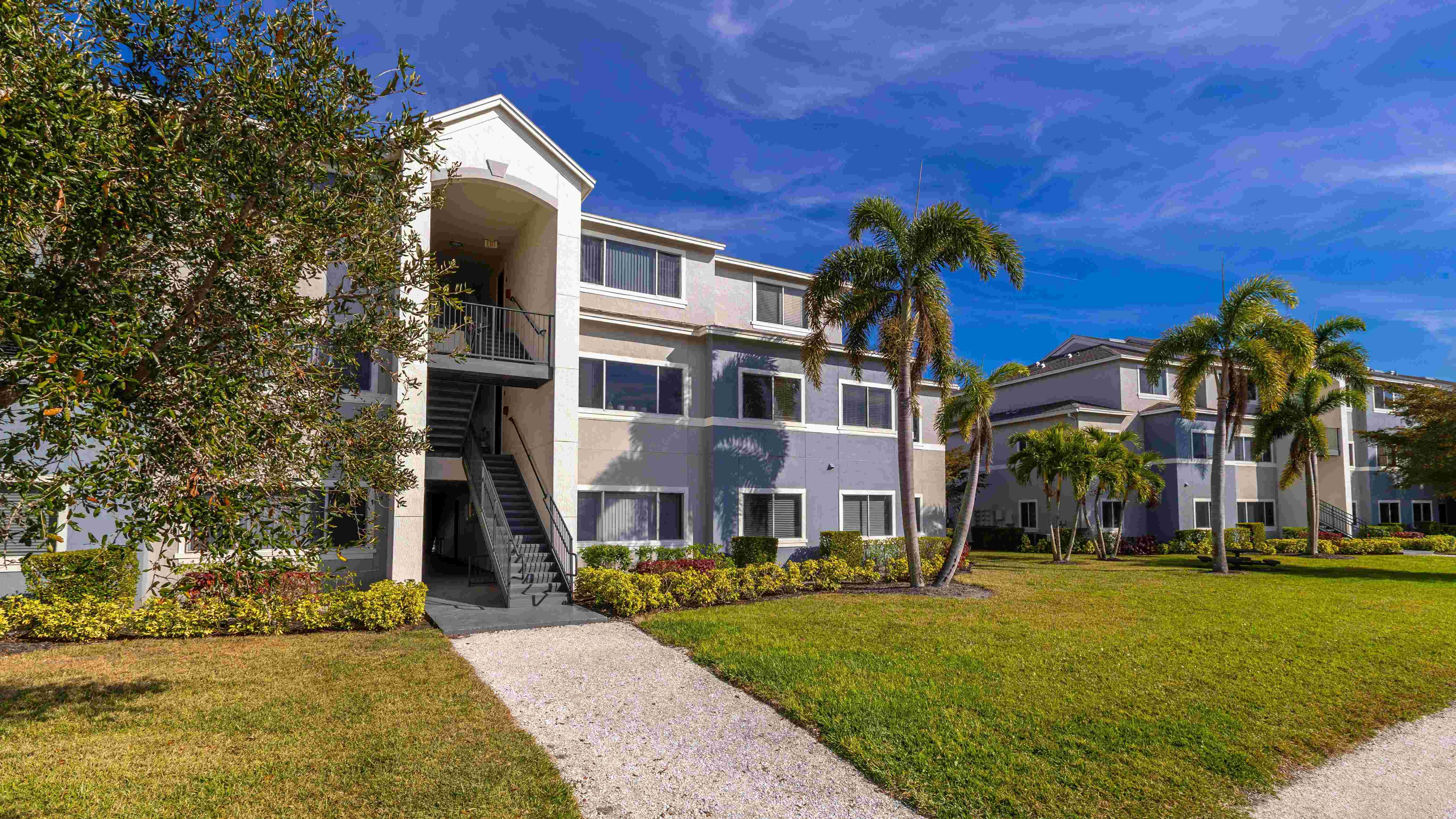 Lexington Palms offers a beautifully maintained community with walking paths, palm trees, and vibrant greenery.