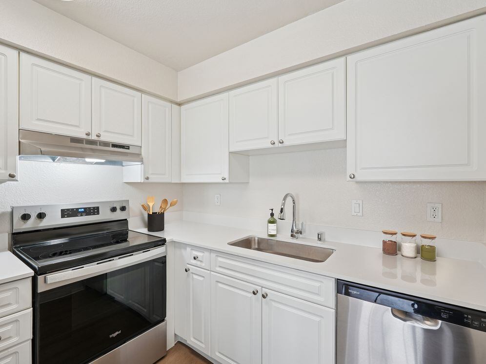 Classic II Collection kitchen with stainless steel appliances, white cabinetry, quartz countertops, and hard surface flooring