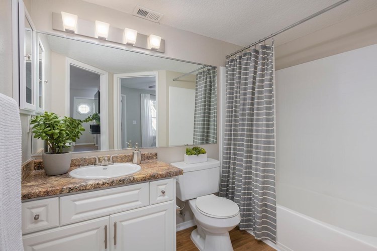 Bathrooms feature granite-style countertops, wood-style flooring, and a large mirror.
