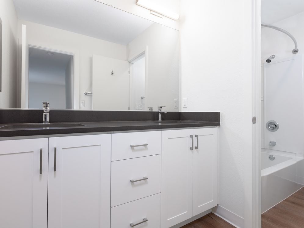 Bathroom with double vanity, grey countertop, white cabinetry and hard surface flooring