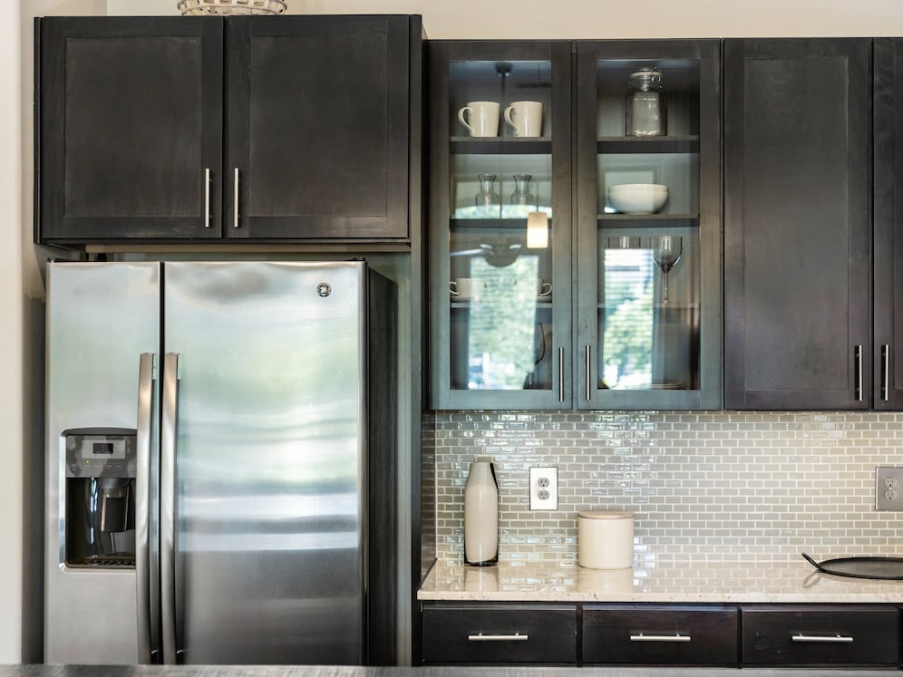 Kitchen with espresso cabinetry, granite countertops, tile backsplash, and stainless steel appliances