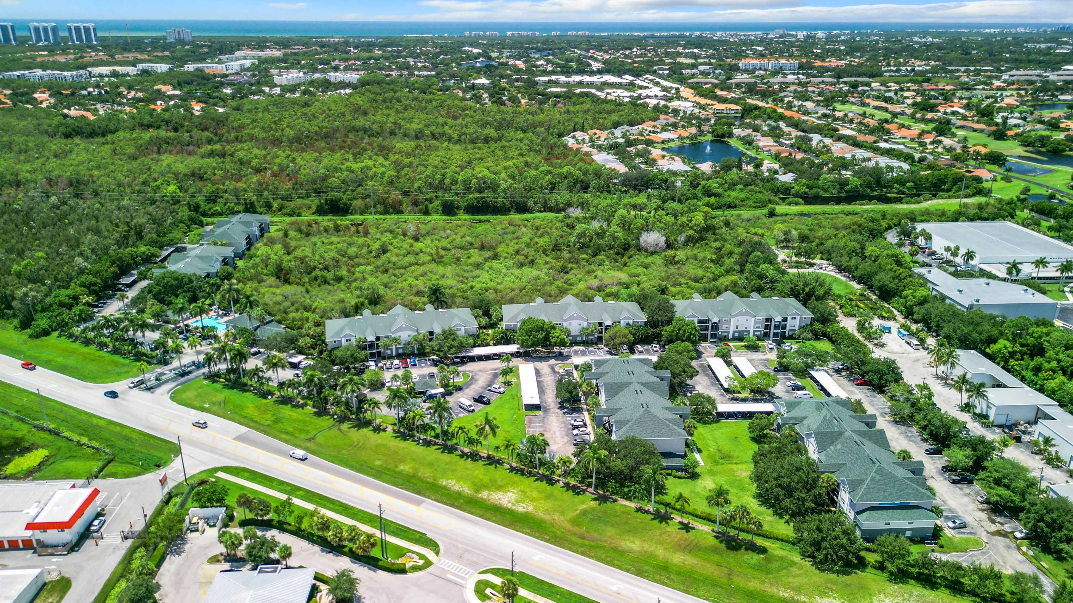 An expansive aerial view of our beautiful community, illustrating the balance of lush green surroundings and proximity to local amenities such as Barefoot Beach, making it an ideal place to call home.