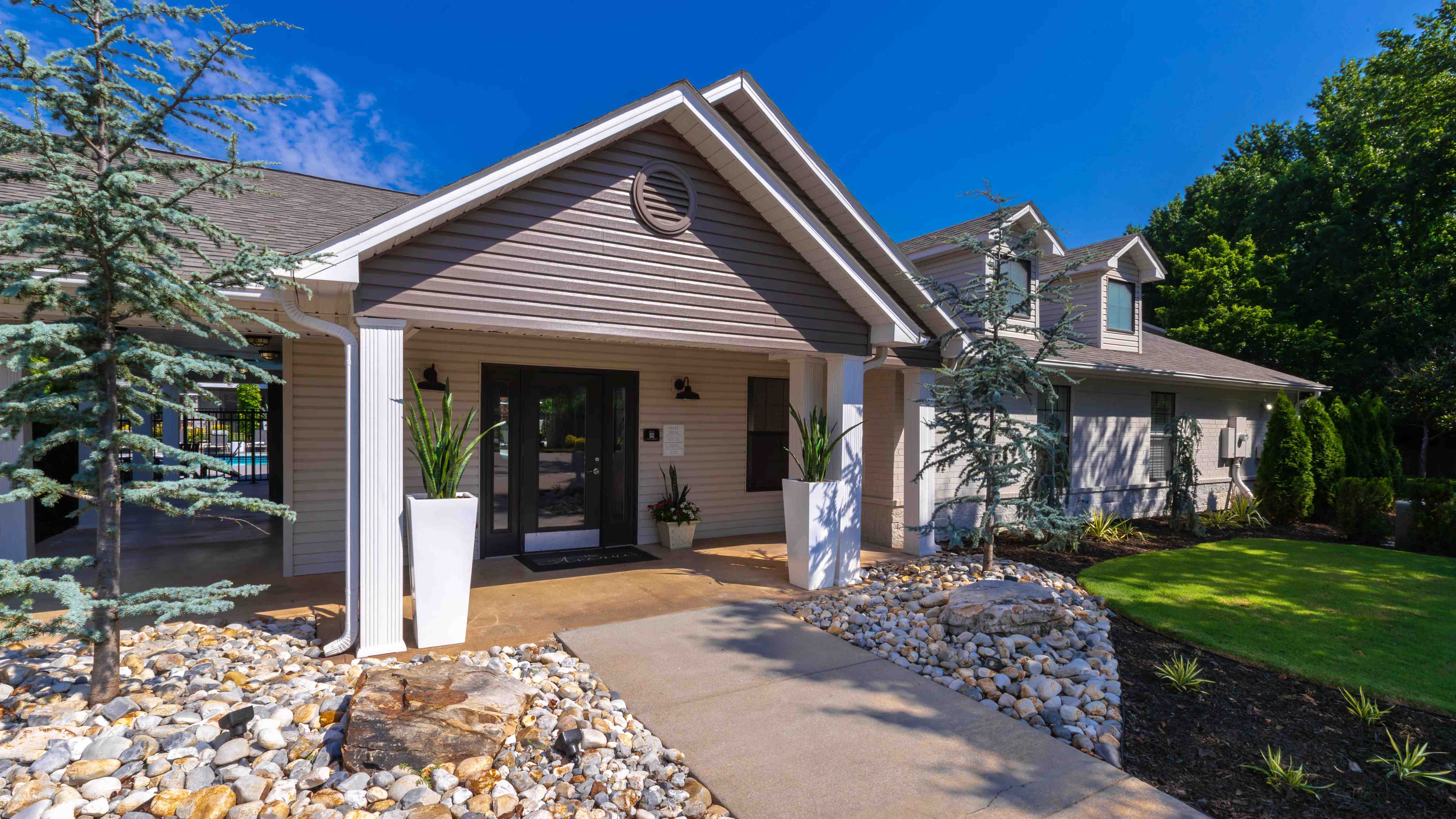 The Avenue's leasing center features a modern entrance with beautiful landscaping, setting the tone for a luxury living experience.