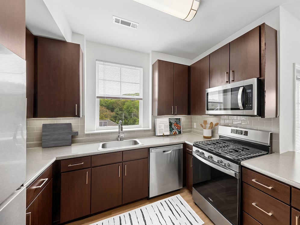 Updated Finishes kitchen with stainless steel appliances, espresso cabinetry, tile backsplash, laminate countertops, and hard surface flooring