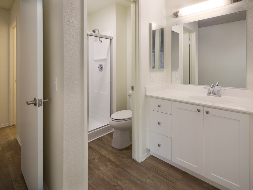 Renovated Package I bath with white cabinetry and hard-surface flooring