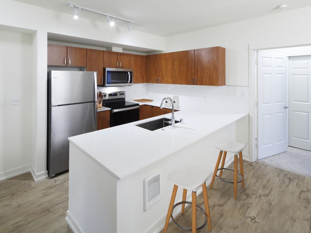 Renovated Package I kitchen with white quartz countertops, oak cabinetry, stainless steel appliances, tile backsplash, and hard surface flooring