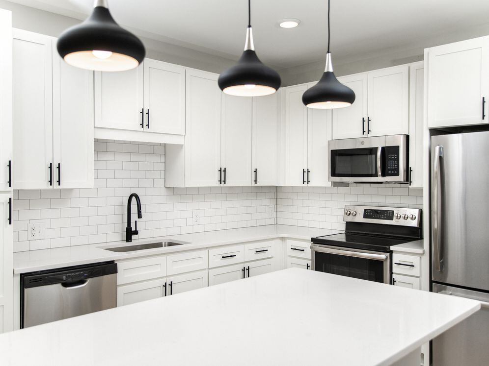 Kitchen with white quartz countertops, white cabinetry, and stainless steel appliances