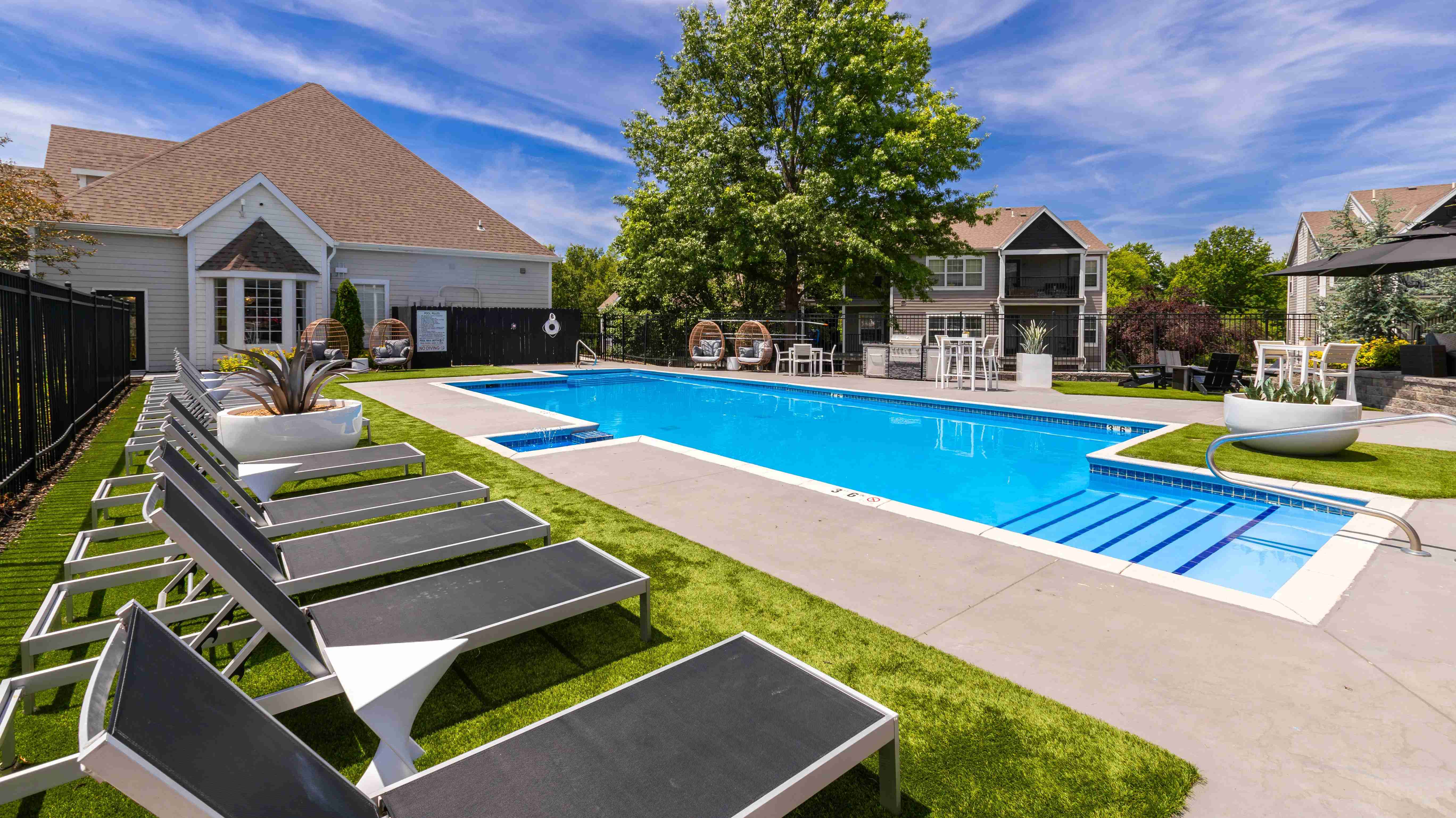 Enjoy a sunny day by the pool featuring comfortable lounge chairs, stylish seating, and a beautifully landscaped setting perfect for relaxation.