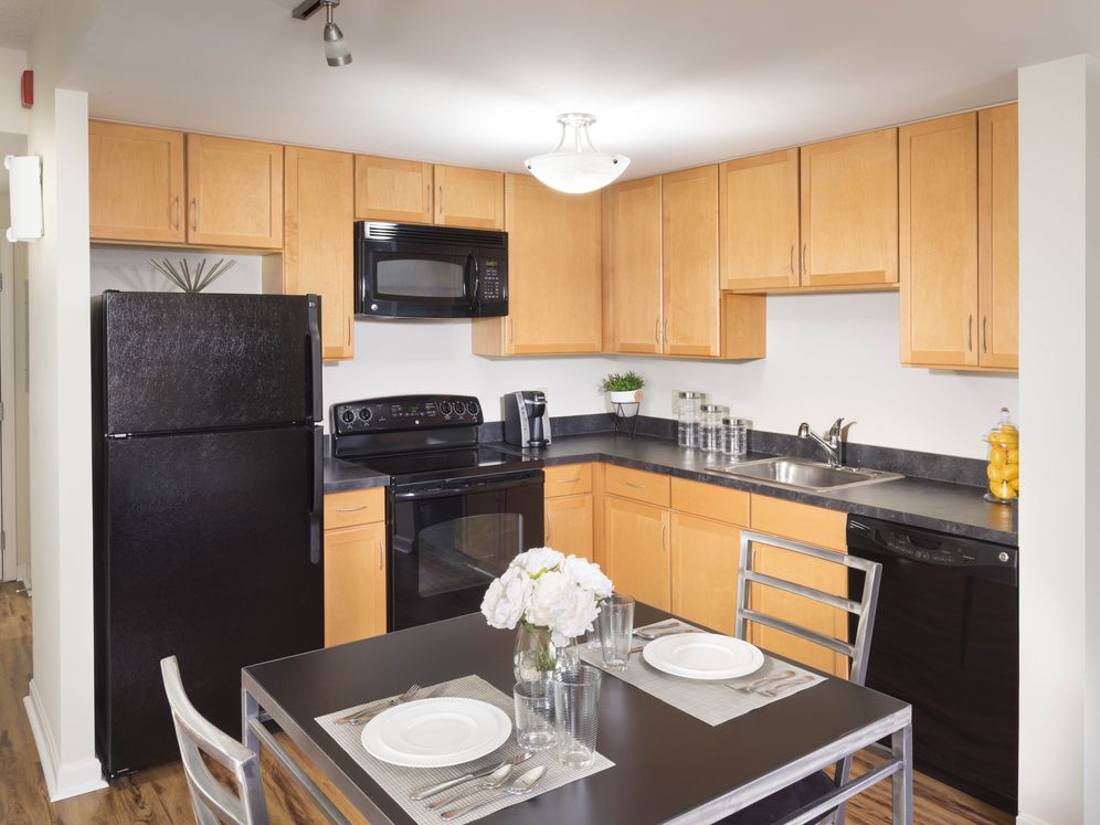 Dining area and kitchen with black appliances, black countertops and hard surface flooring