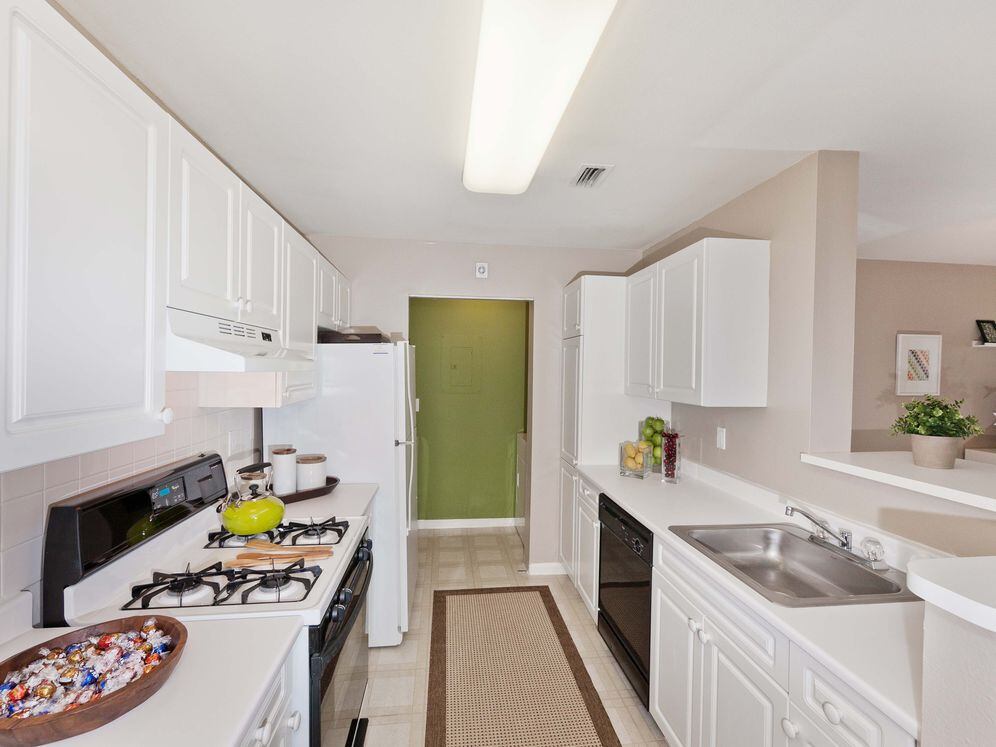 Classic Scheme kitchen with white shaker cabinetry, white laminate countertops, white tile backsplash, black and white appliances, and hard surface flooring