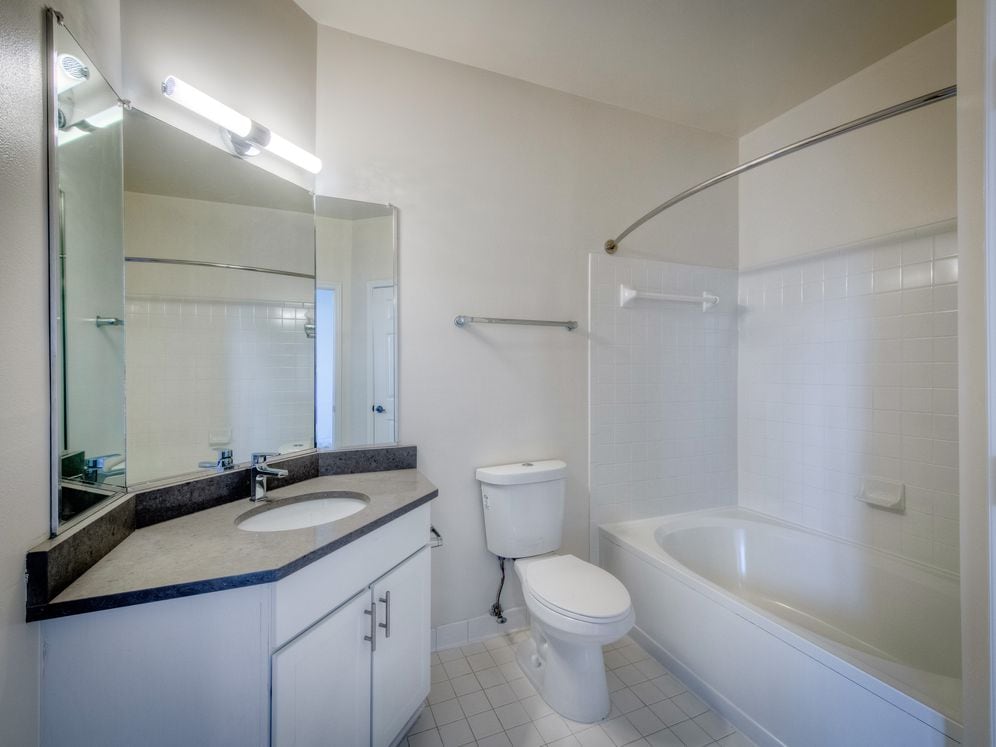 Renovated Package II bathroom with white cabinetry, grey quartz countertop, and hard surface flooring