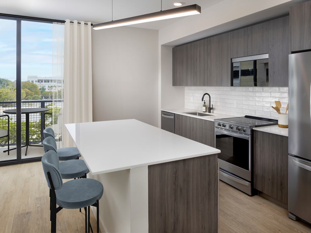 Upgrade Collection II Three-bedroom apartment kitchen with espresso cabinetry, white tile backsplash, white quartz countertop, and hard-surface vinyl plank flooring