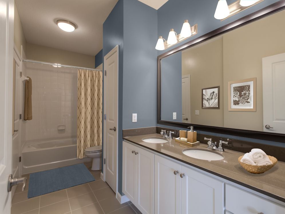 Double vanity bath with quartz stone countertop, white cabinetry and linen closet