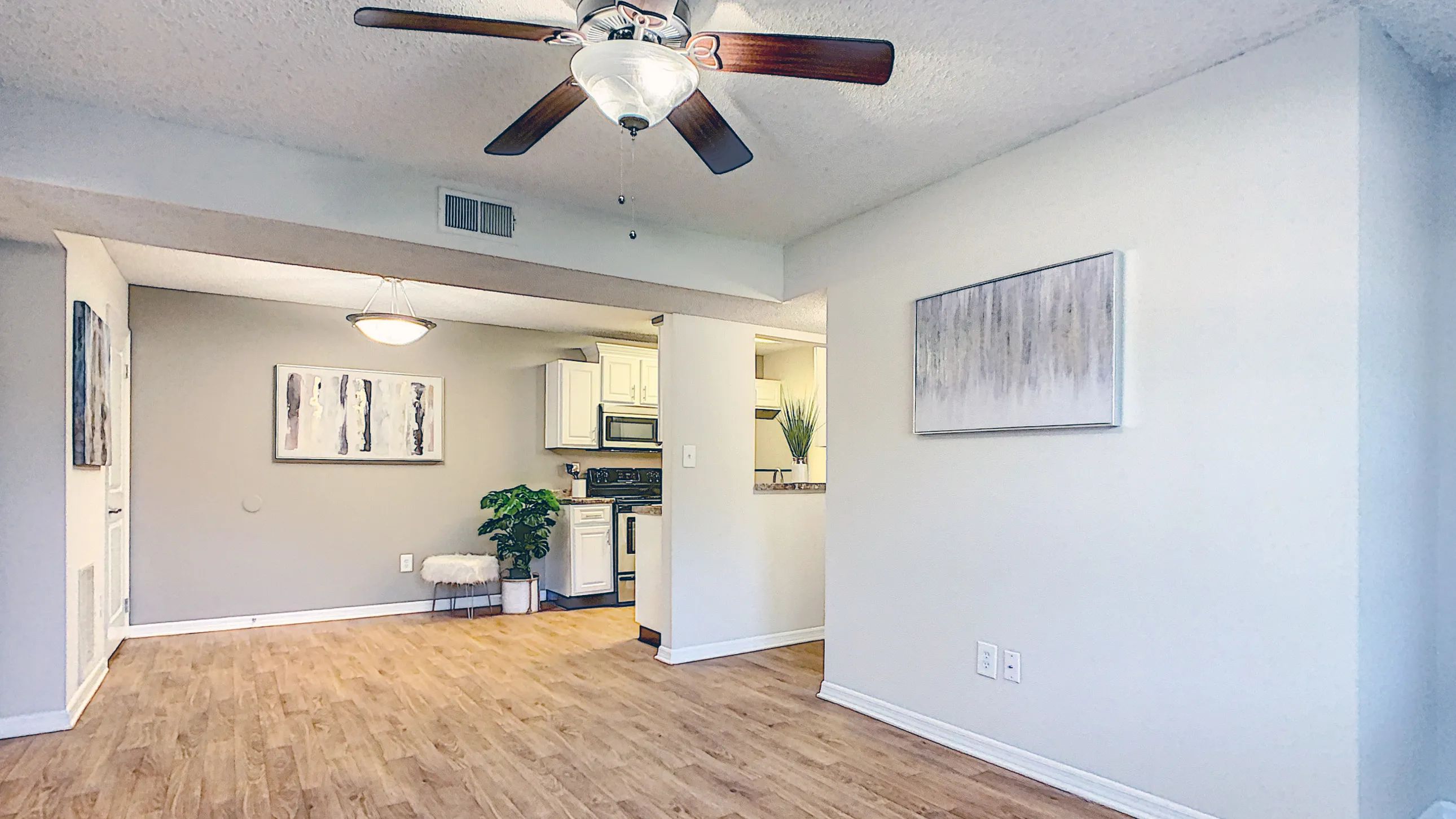 Airy open floor plans with wood-style flooring and ceiling fans offer an elegant, communal living experience. 