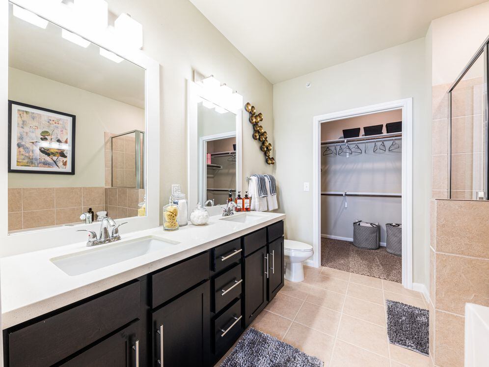Baths with dark cabinetry, white quartz countertops, and hard surface flooring