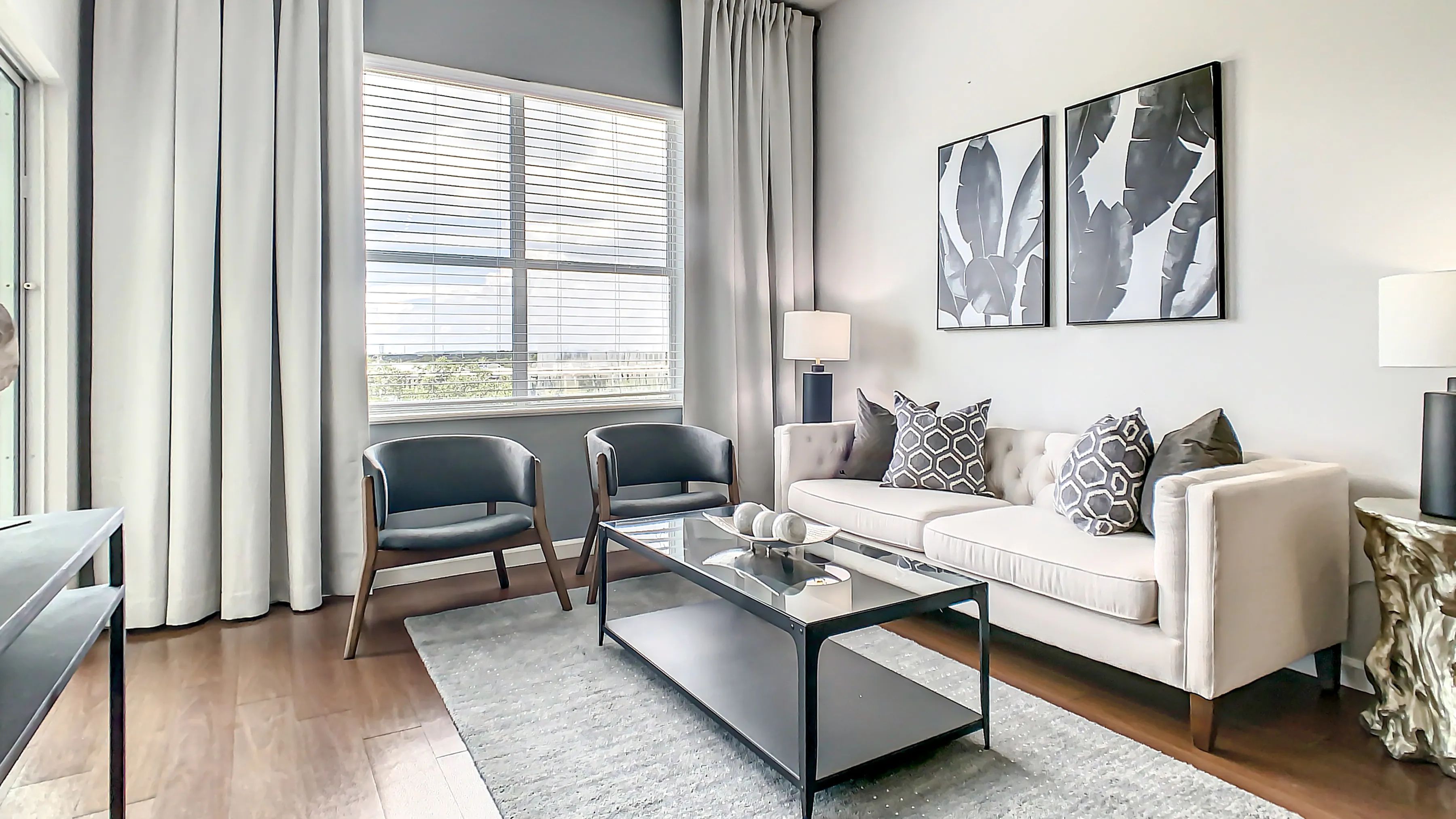 Bask in our spacious living room's classic comfort, adorned with wood-style flooring and large windows, welcoming in ample natural light.