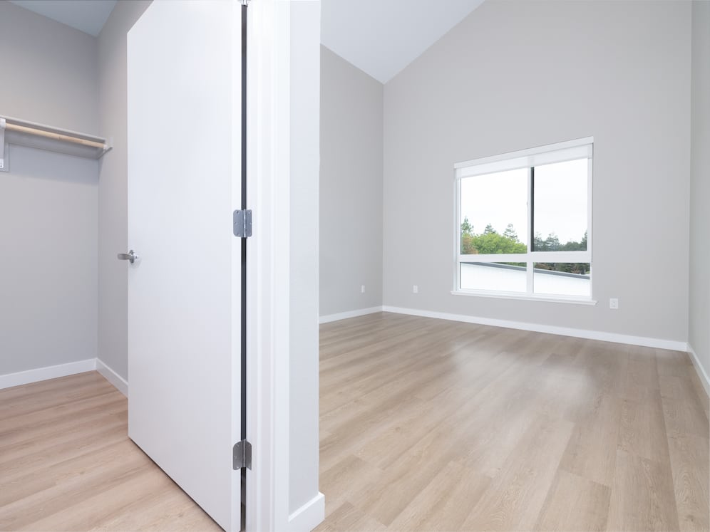 Signature Collection II Primary bedroom and walk-in closet with hard-surface vinyl plank flooring