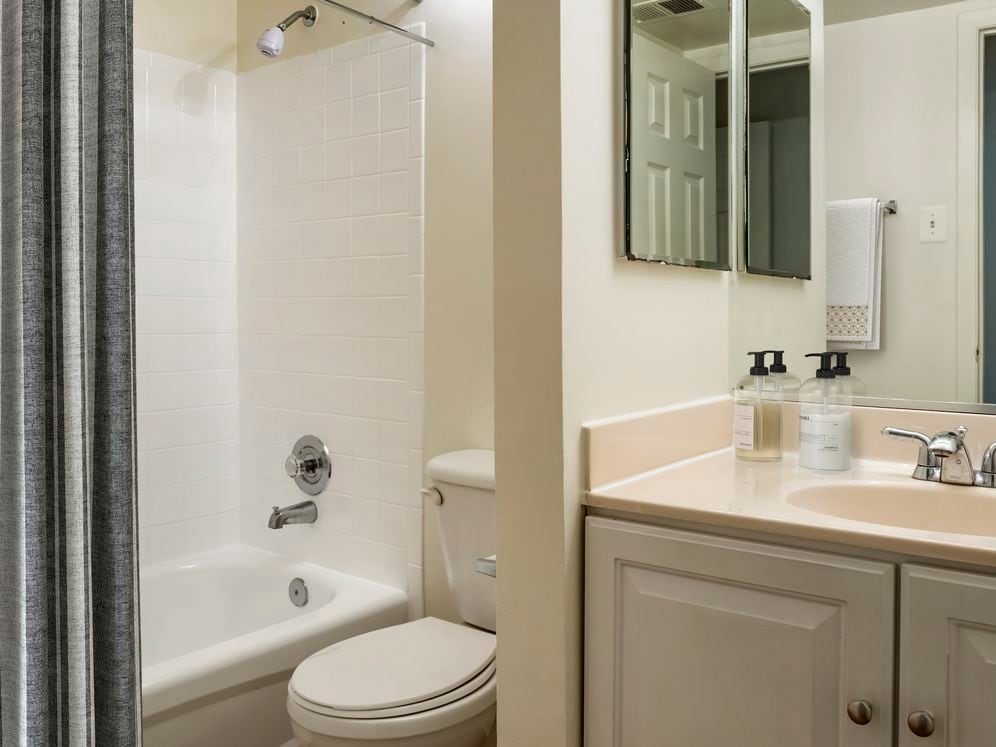 Renovated Package I bath featuring white cabinetry and countertops