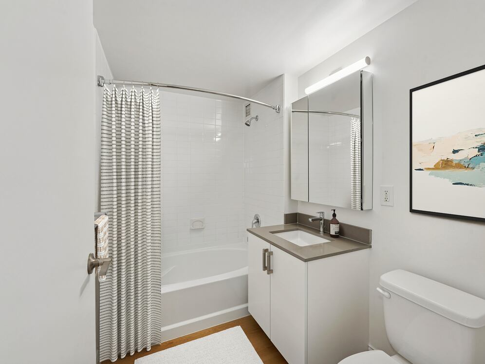 Renovated Package I bath with grey quartz countertop, white cabinetry, and hard-surface flooring